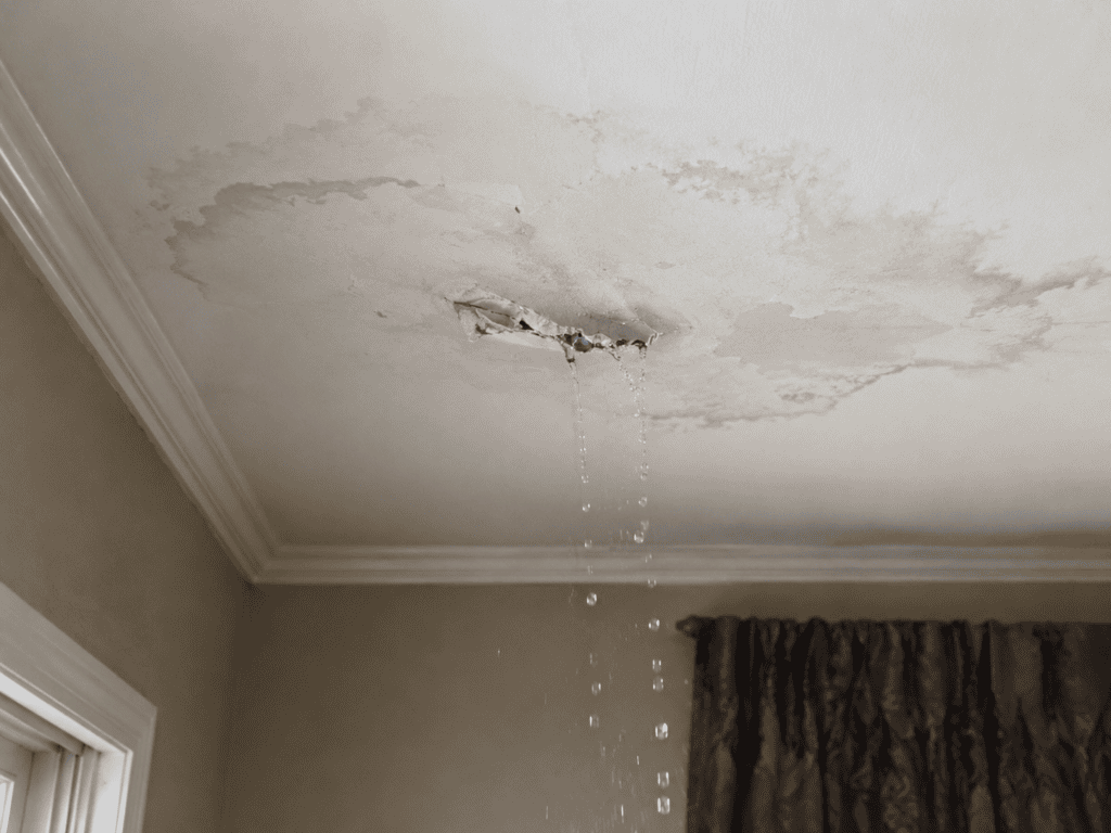 Water leaking through a stained ceiling in a residential home after storm damage, showing an active roof leak requiring emergency roof repair.